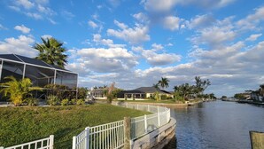 A waterfront property with a covered outdoor area, a canal, and residential buildings.