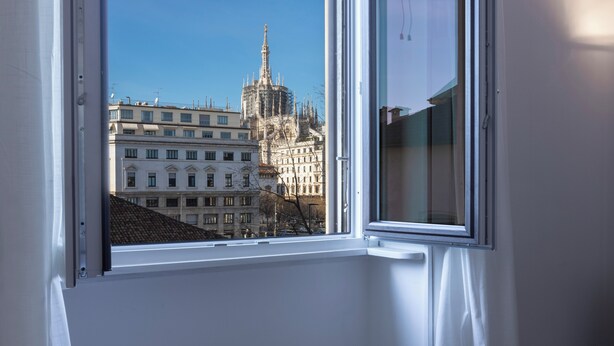 A window with a view of a historic building with intricate architecture and a clear blue sky. - Italianway Comfort - Merlo 1 E (Milan)