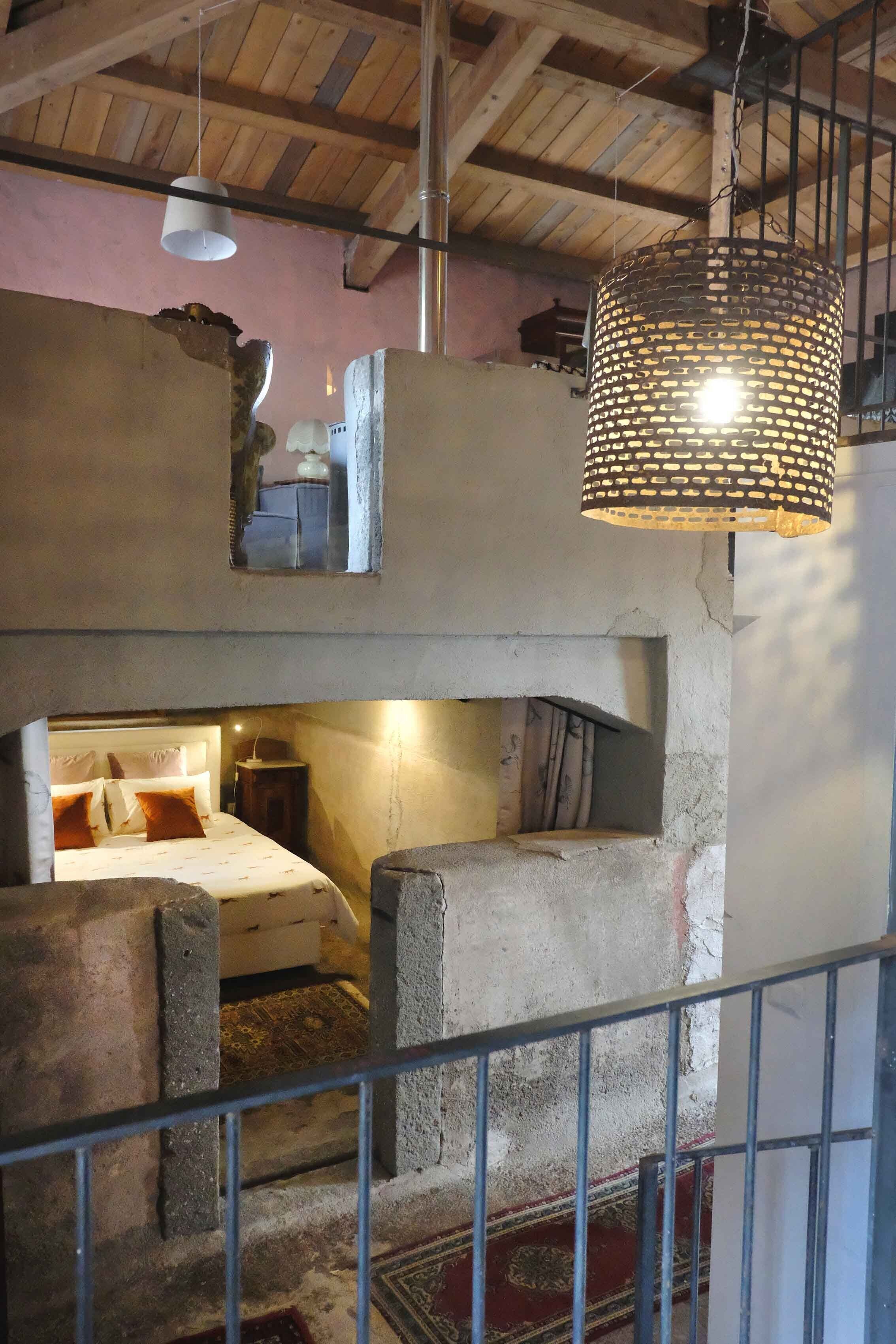 A rustic room with a bed, a small table, and a hanging light fixture.