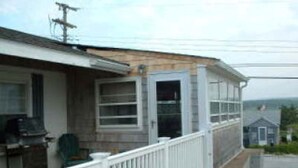 A single-story house with a porch, a garage, and a small attached shed. - 217 N Shore Blvd (Sandwich)
