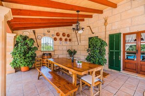 Cozy dining area with a wooden table and benches, surrounded by lush greenery and exposed beams.
