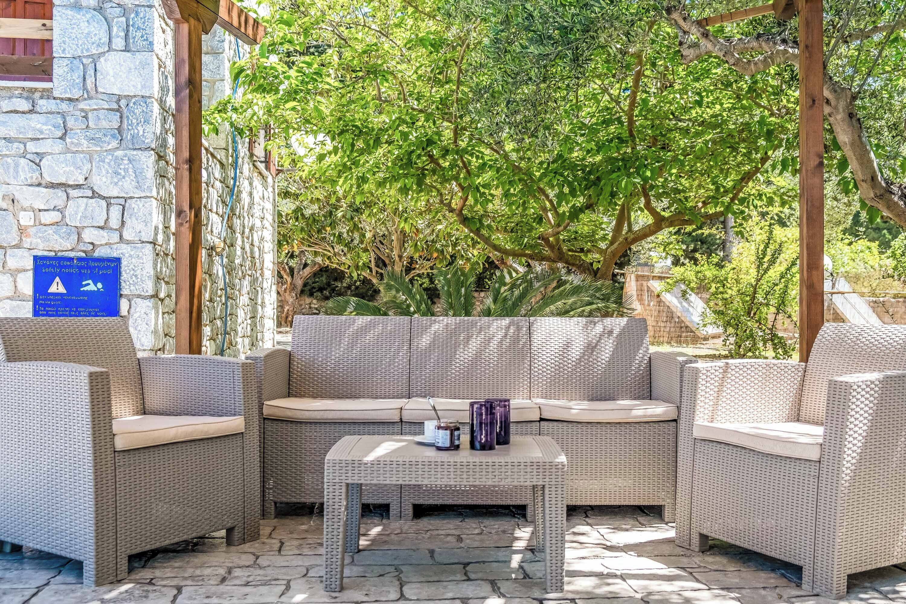 A wicker sofa set with a table, stone walls, and a sign indicating a road lengthening.