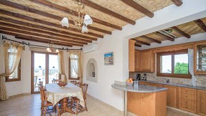 A spacious kitchen with wooden cabinets, a central island, and a dining area with a table and chairs.