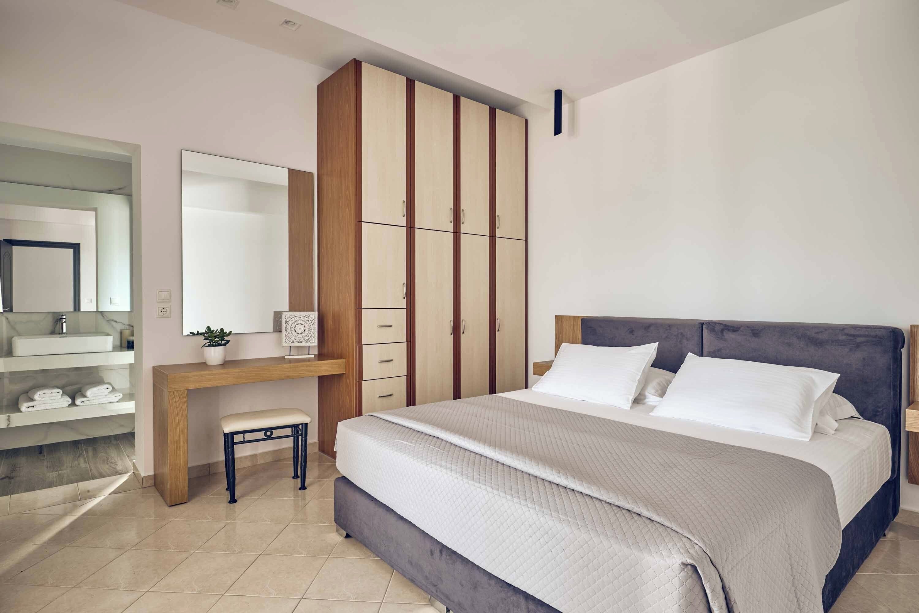 Quarto com cama, escrivaninha, guarda-roupa e espelho.