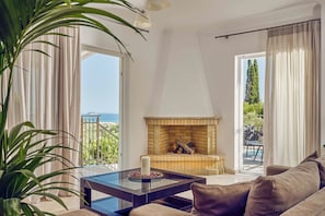 Un salon avec une cheminée, une table basse en verre, un canapé et une vue sur l’extérieur.
