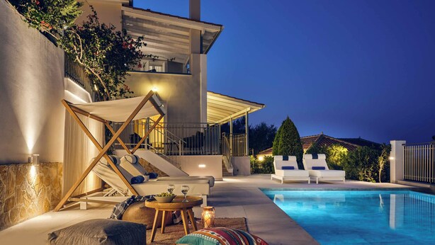 Un’area piscina moderna all'aperto con lettini, un set da pranzo e una scala che conduce a un balcone.