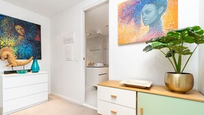 A modern bathroom with a shower, a sink, and a toilet. There is a white cabinet with drawers and a mirror above it.