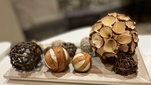 A display of decorative items including a spherical object with a woven pattern, a spherical object with a striped pattern, and a spherical object with a textured surface. - Le Cocon Charmant Studio (Nîmes)