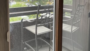 A room with a sliding glass door leading to an outdoor balcony with two chairs and a table. -  1 bdrm condo. Indoor parking garage. Secure bldg access.  90 day minimum stay (Anchorage)