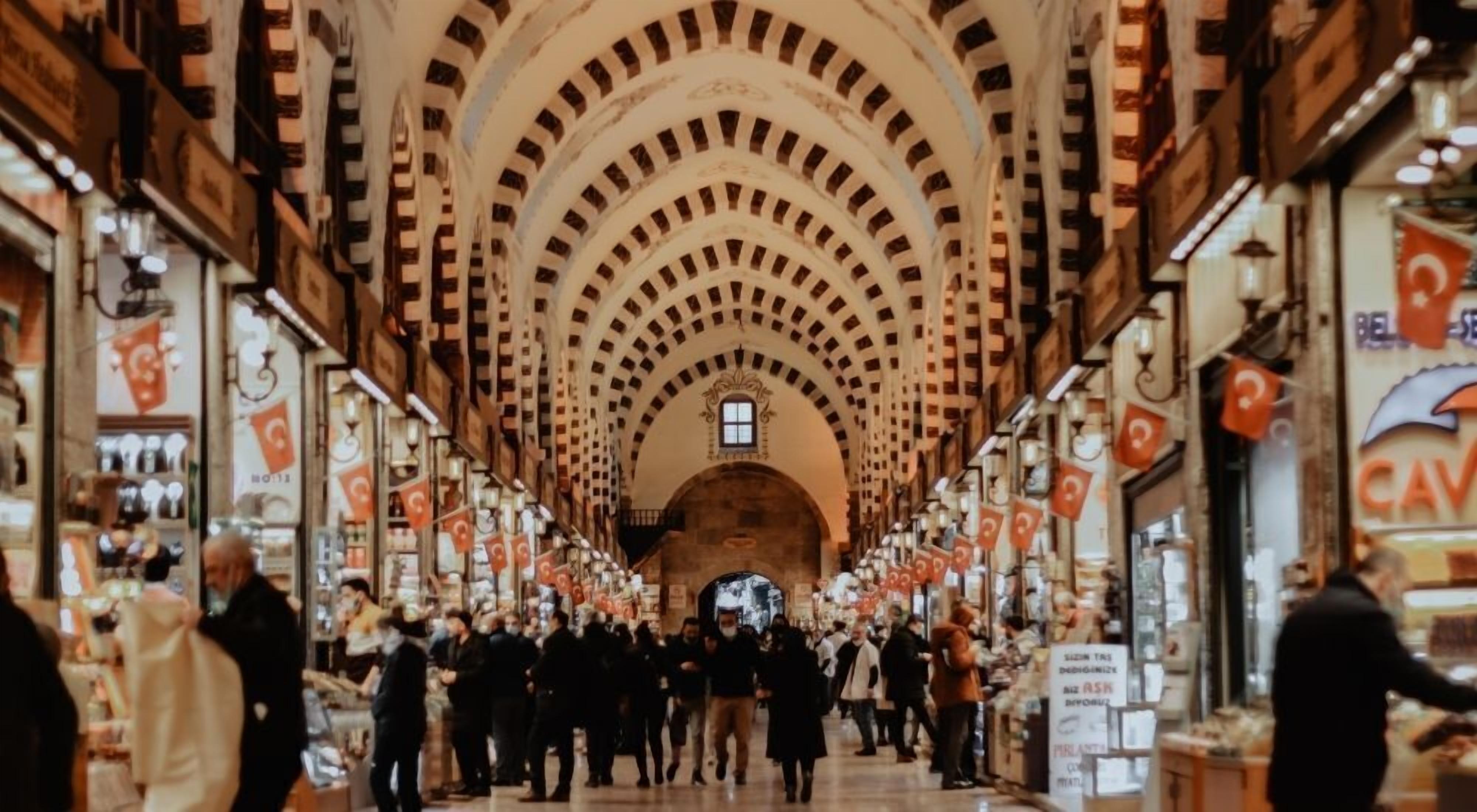 A crowded indoor market with arched ceilings and various shops on either side.