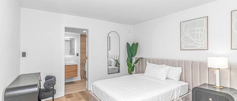 A modern bedroom with a bed, bedside table, and a desk.
