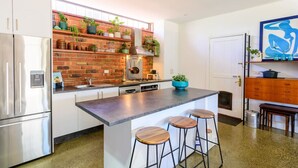 A modern kitchen with a brick backsplash, stainless steel appliances, and a central island with bar stools.