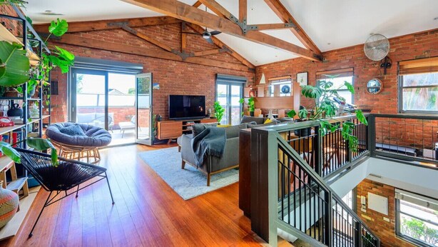 A spacious living area with exposed wooden beams, a large TV, and multiple seating options.