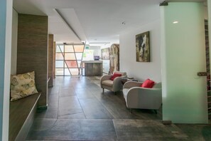 A modern hotel lobby with a reception desk, seating area, and a staircase. - Yucatán - 1 Bedroom in Playa Near 5th At 38th Street (Playa del Carmen)