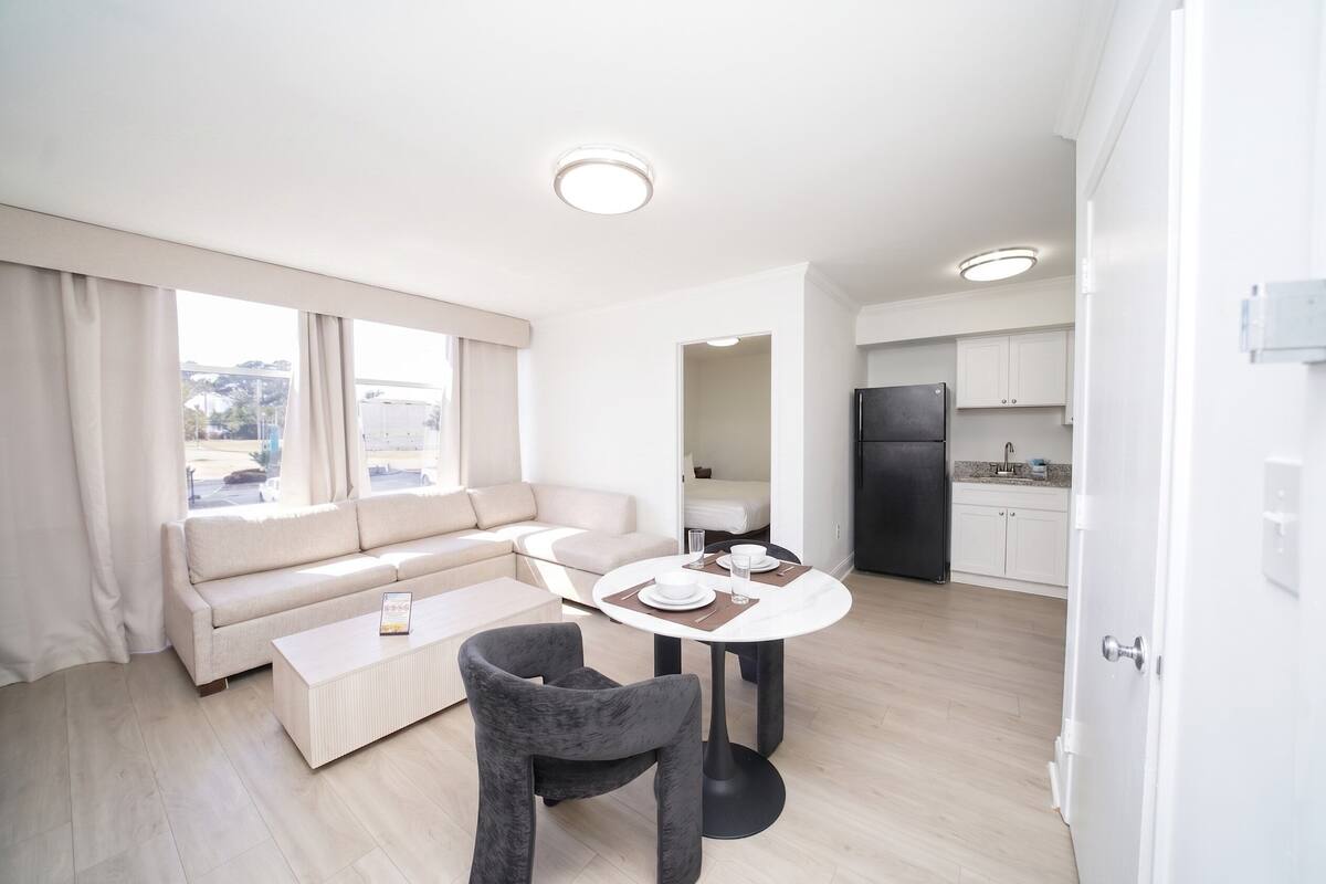 A modern living room with a sofa, a coffee table, and a dining table set for two.