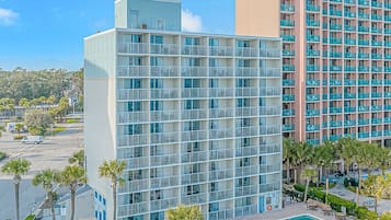 A hotel with multiple floors, a swimming pool, and a parking lot.
