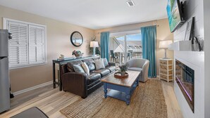 A living room with a sofa, coffee table, and a TV mounted on the wall. - 321 Oceanfront Villa | Walk to Coligny + Pools | Washer/Dryer (Hilton Head Island)