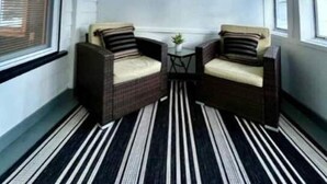 A room with two wicker chairs, a small table, and a striped floor. - Entire Home N. Conway - Central Location, Saco, Skiing, Shopping (Conway)