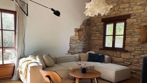 Una sala de estar moderna con una pared de piedra, un ventanal grande, un sofá, una mesa de centro y una lámpara colgante.