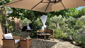 Un patio al aire libre con suelo de piedra, mobiliario de mimbre y una sombrilla grande que da sombra.