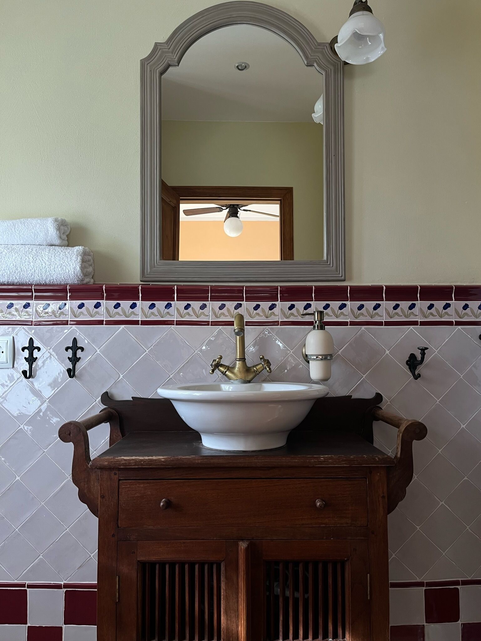 A bathroom with a white sink, wooden cabinet, and a mirror above it.