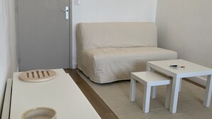 Ein schlicht eingerichteter Raum mit einer Couch, einem kleinen Tisch, einem Couchtisch und einem Schrank.