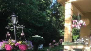 Un giardino con una statua, fioriere pensili e un gazebo.