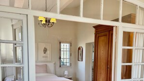 Une chambre à coucher avec un lit, une table de chevet, une lampe, une armoire en bois et une fenêtre.
