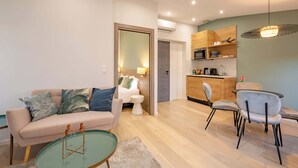 A modern living room with a sofa, coffee table, and chairs. There is a kitchen area with cabinets and a dining table. - 1 Bedroom : Scandinavian Urban 4 in city center (Cannes)