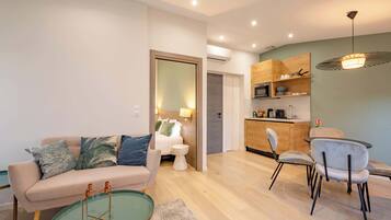 Un salon moderne comprenant un canapé, une table basse et des fauteuils. On y trouve également un coin cuisine avec des placards et une table à manger.