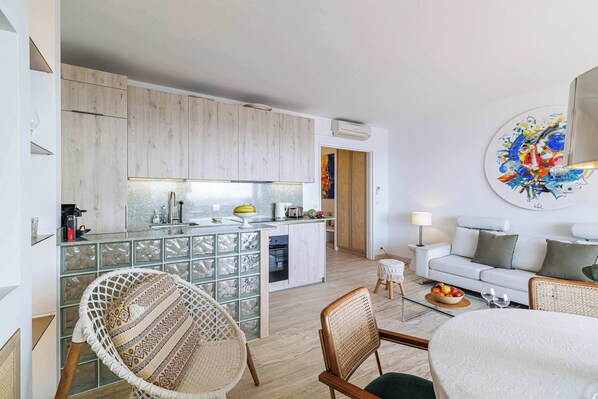 Une cuisine moderne avec des meubles en bois, un pare-feu en verre et un coin repas comprenant des chaises en osier et une table ronde.