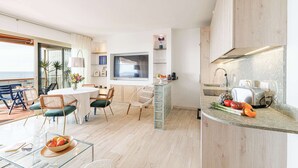Una cocina moderna con un tostador empotrado, un comedor con mesa y sillas, y vista al mar a través de amplios ventanales.