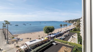 Vista de la playa con una hilera de carpas, un estacionamiento y barcos en el agua.