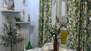 Un coin repas avec une table dressée pour quatre personnes, agrémenté d’une nappe à motifs bleus et blancs, de bougeoirs et d’objets décoratifs.