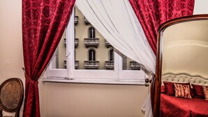Une pièce avec un lit, une chaise et une fenêtre ornée de rideaux rouges.