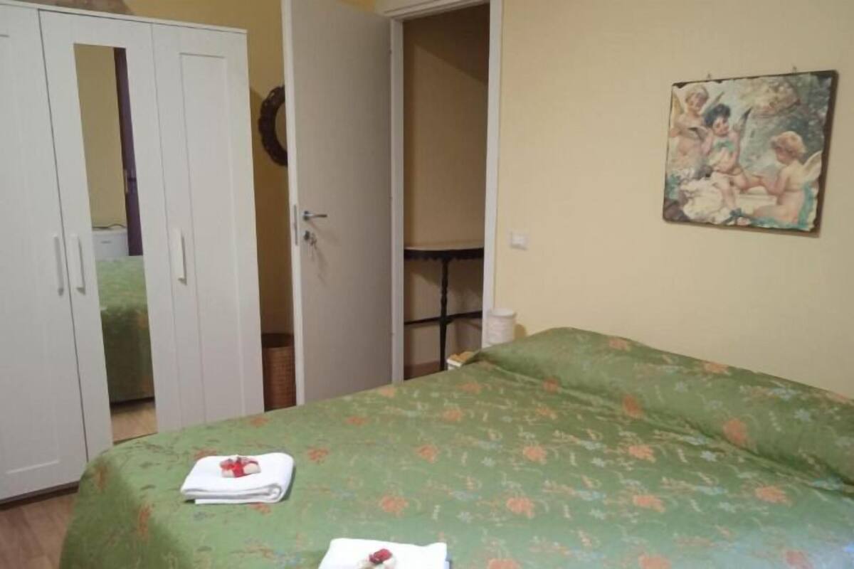 A bedroom with a bed, a wardrobe, and a painting on the wall.