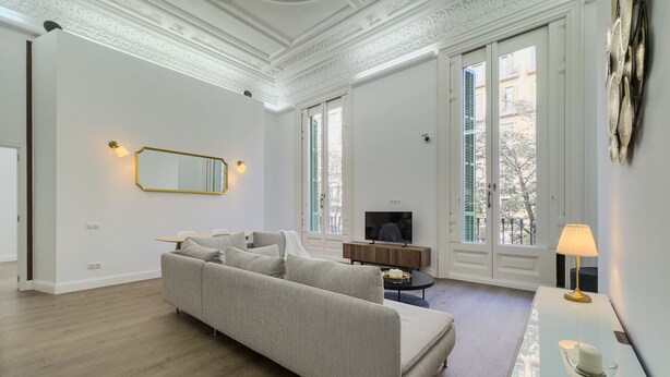 Un salón amplio con un sofá grande, un televisor y una zona de comedor con una mesa y sillas.