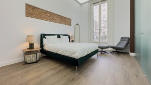 Un dormitorio con una cama, una silla, una lámpara y una ventana.