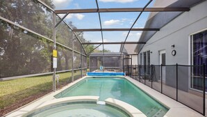 A swimming pool with a covered area, surrounded by a fence, and adjacent to a building with large windows. - 'Disney Dreams' Spacious 4 Bed home with Private pool & Spa (Clermont)