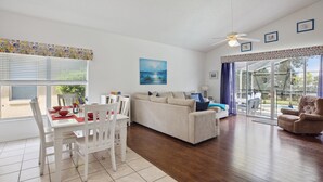 A spacious living room with a white sofa, a dining table with chairs, and a ceiling fan. - 'Disney Dreams' Spacious 4 Bed home with Private pool & Spa (Clermont)