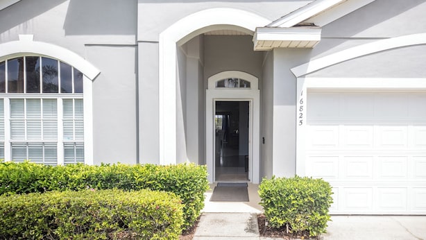 A modern two-story house with a garage, a covered entryway, and a large window with shutters. - 'Disney Dreams' Spacious 4 Bed home with Private pool & Spa (Clermont)