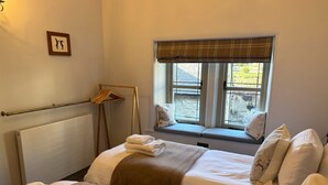 Una camera d'albergo con due letti, una finestra vista, un termosifone e un quadro appeso al muro.