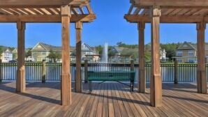 A wooden deck with a bench, a fountain, and houses in the background. - Family Escape Near Disney | Resort Amenities (Kissimmee)