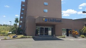 A UniHotel building with a flat roof, multiple windows, and a parking lot in front.