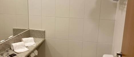 Un baño pequeño y limpio con lavabo, espejo, inodoro y ducha.