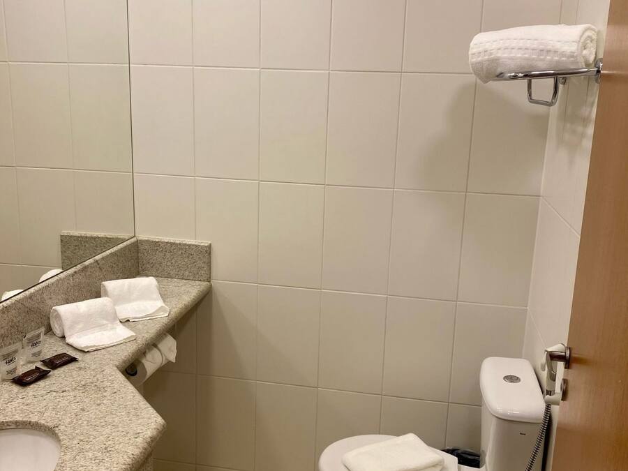 Un baño pequeño y limpio con lavabo, espejo, inodoro y ducha.