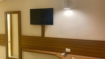 Huoneessa on puinen penkki, seinälle asennettu televisio ja peili.
