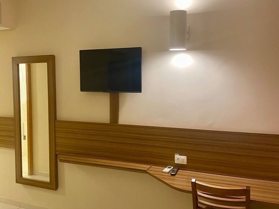 A room with a wooden bench, a television mounted on the wall, and a mirror.