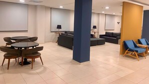 A modern hotel lobby with a seating area, a sofa, and a projector screen.