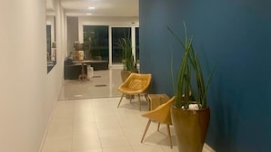 A spacious hallway with a blue accent wall, potted plants, and modern furniture.